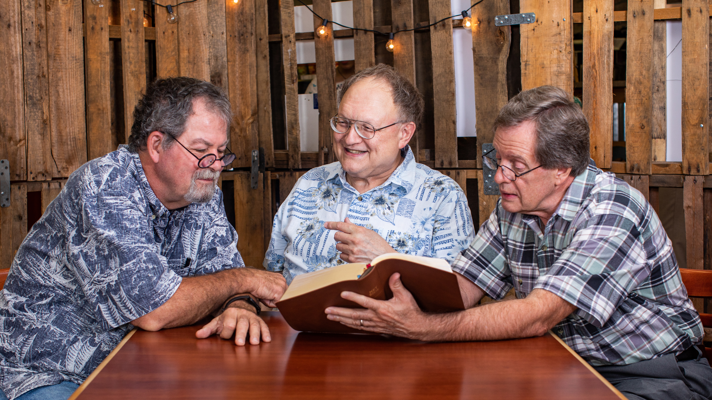 Dr. Wallace, Dr. Harris, and Dr. Chisholm looking through a Bible together