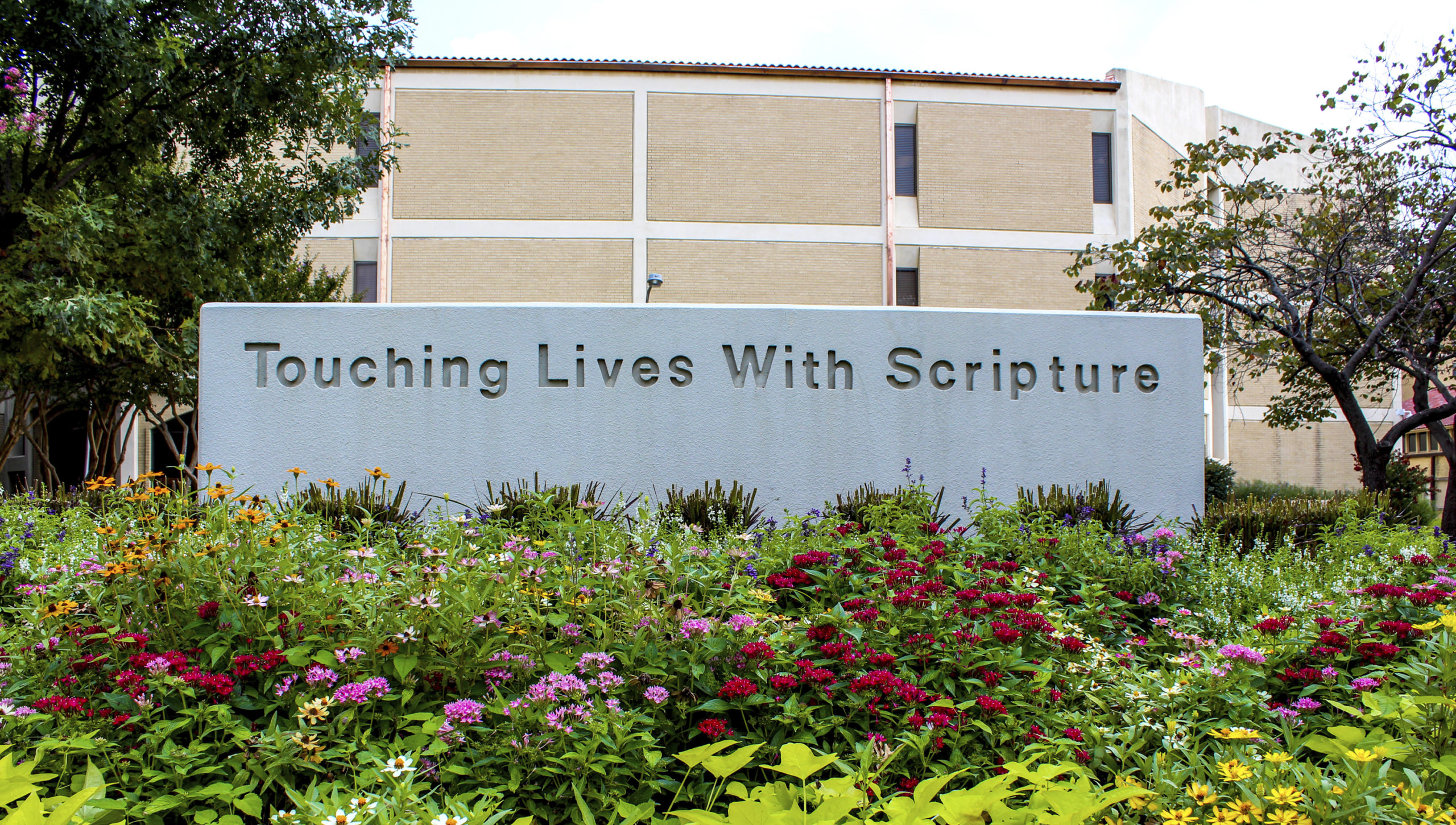 sign on campus that reads touching lives with scripture